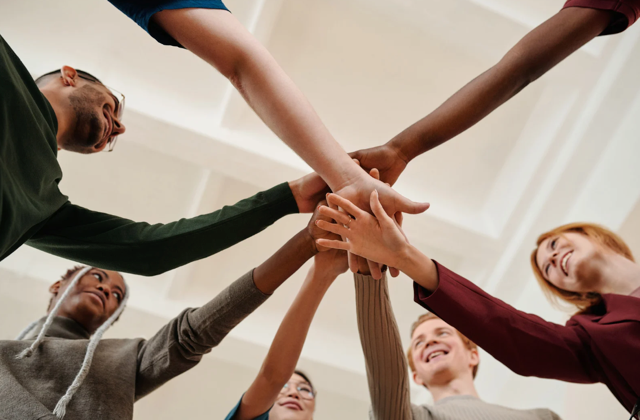 People pile hands on top of each other in solidarity